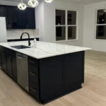 Modern kitchen with dark cabinets, white island countertop, and stainless steel appliances